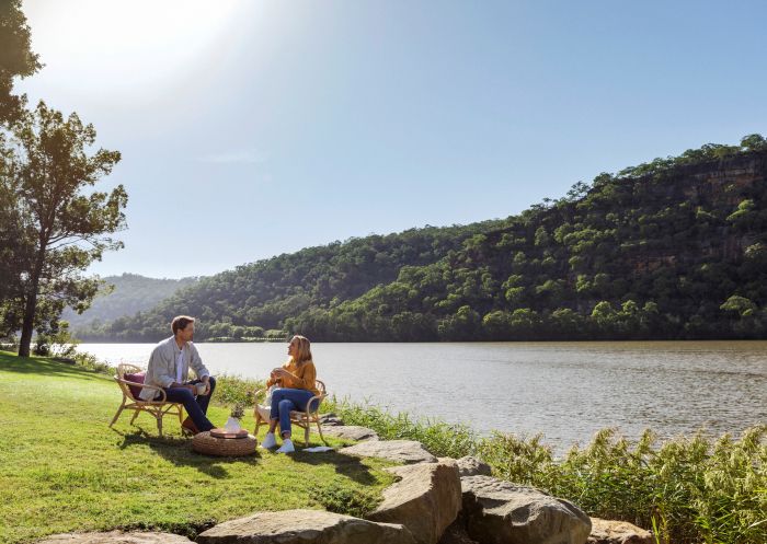 Couple enjoying a morning coffee by the Hawkesbury River at Del Rio Resort, Webbs Creek