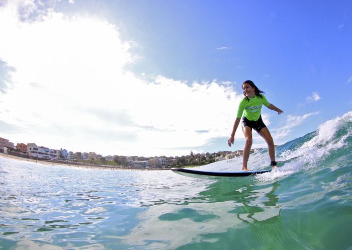 Lets Go Surfing, Bondi Beach Girl catching a wave at Bondi Beach with surf school Lets Go Surfing
