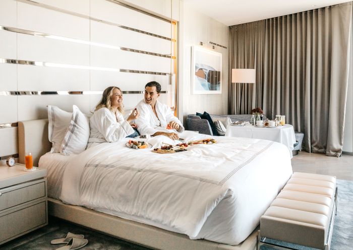 Couple enjoying breakfast in bed at Crown Sydney, Barangaroo