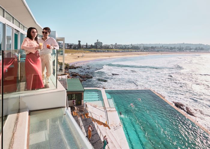 Couple enjoying a drink on the balcony at Icebergs Dining Room and Bar, Bondi