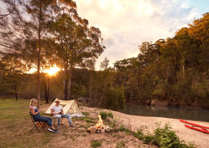 Couple enjoying a campfire by their tent on the Hawkesbury River, Lower MacDonald