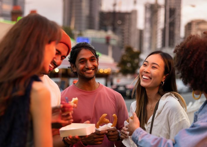 Friends enjoying takeaway food and drink in Little India, Harris Park