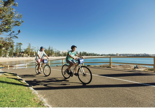 Father and son enjoying a bike ride at Manly Beach 