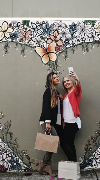 Friends taking a selfie in front of Aaron Favaloro street art, Paddington