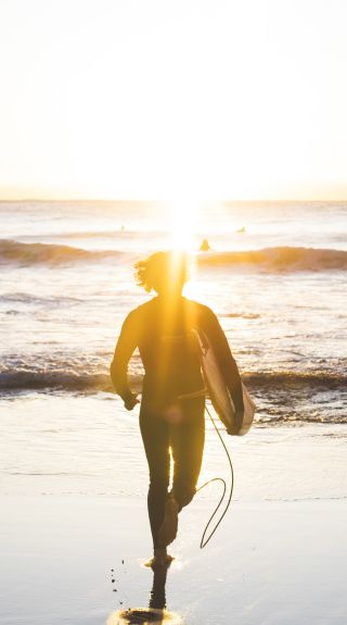 Man heading into the surf at Whale Beach on Sydney's Northern Beaches