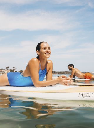 Couple enjoying a stand up paddleboarding experience in Shoal Bay, Port Stephens, North Coast