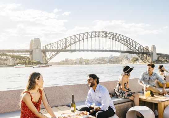 Couple enjoying food and drink with harbour views at Opera Bar, Sydney.